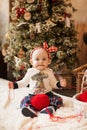 Funny baby sitting with a ball of red thread on the background of a Christmas tree. concept of gift with your own hands Royalty Free Stock Photo