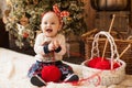 Funny baby sitting with a ball of red thread on the background of a Christmas tree. concept of gift with your own hands Royalty Free Stock Photo