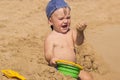 Funny baby is sitting on the beach and in the hand squeezes the wet sand Royalty Free Stock Photo