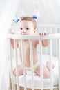 Funny baby sitting in a round white crib