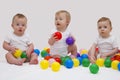 Funny baby triplets smiliing and playing with colorful balls. Studio shot Royalty Free Stock Photo