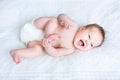 Funny baby wearing diaper playing with her feet Royalty Free Stock Photo