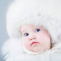 Funny baby in white snow suit and big fur hat Royalty Free Stock Photo