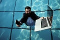 Funny bearded business man in suit using phone and laptop in swimming pool. Concept of young people working mobile Royalty Free Stock Photo