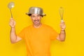 Funny bearded crazy hispanic man with a saucepan on his head and other kitchen utensils in his hands. Cooking. crazy