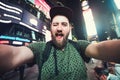 Funny bearded man backpacker smiling and taking selfie photo on Times Square in New York while travel across USA