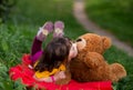 Funny beautiful girl child in a yellow T-shirt lies on a red plaid and kisses a teddy bear Royalty Free Stock Photo