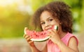 Cute Black girl eating watermelon outdoors in hot summer. Smilhing baby looking at camera, healthy food Royalty Free Stock Photo