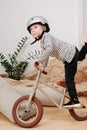 Funny blond boy standing on one foot on a small two wheel bike inside a room Royalty Free Stock Photo