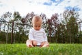 Funny blond cute baby sitting in grass and playing with car toy Royalty Free Stock Photo