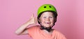 Funny blond kid in helmet missing tooth giving thumb up sign. Child with two upper missing teeth isolated on pink