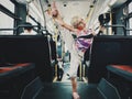 Funny blonde Caucasian girl riding on a bus and stretching