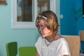 Funny boring, hostile unhappy little girl sitting with painted face at kids club