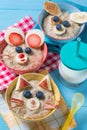 Funny bowls with oat porridge with cat, dog and mouse faces made of fruits and berries, food for kids idea Royalty Free Stock Photo