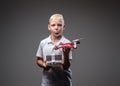 Funny boy boxer with blonde hair dressed in a white t-shirt holds a quadcopter and control remote.