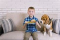 Funny boy with dog beagle eating fried potatoes with a hamburger