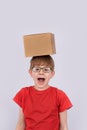 Funny boy in glasses put box on his head. Vertical frame