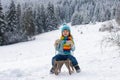 Funny boy having fun with a sleigh in winter. Cute children playing in a snow on snowy nature landscape. Winter Royalty Free Stock Photo