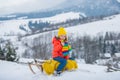 Funny boy having fun with a sleigh in winter. Cute children playing in a snow on snowy nature landscape. Winter fun kids Royalty Free Stock Photo