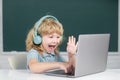Funny boy in headphones study online, child in earphones take Internet web lesson. Excited amazed kids emotions.