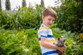 Funny boy hugging a cat with lots of love. Portrait of child holding on hands a Kitten. Playing with a cat on village countryside Royalty Free Stock Photo