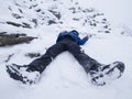 Funny boy laying in snowdrift. Kid play game in fresh snow on stony hill Royalty Free Stock Photo