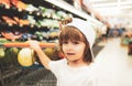 Funny boy with shopping cart full of fresh organic vegetables and fruits standing in grocery department of food store or Royalty Free Stock Photo