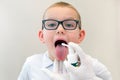 Funny boy with sore throat wearing glasses, doctor uses medicine aerosol for throat