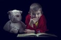Funny boy with a stuffed dog reading a book for bed time in arti Royalty Free Stock Photo