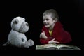Funny boy with a stuffed dog reading a book for bed time in artistic conversion Royalty Free Stock Photo