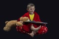 Funny boy with teddy bear reading a book before bed time Royalty Free Stock Photo