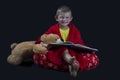 Funny boy with teddy bear reading a book before bed time Royalty Free Stock Photo