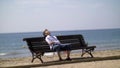Funny boy is tired and trying to sleep on a bench near the beach Royalty Free Stock Photo
