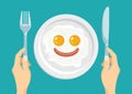 Funny breakfast. Fried eggs and sausage in the shape of smiling face on white plate. Hands hold knife and  fork. Royalty Free Stock Photo