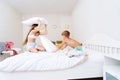 Funny brother and sister fighting pillow on bed morning bedroom kids boy and girl playing together Royalty Free Stock Photo