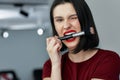 Funny brunette female with red lips bites a brush making make-up. Happy young woman making herself makeup with a brush with Royalty Free Stock Photo