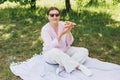 Funny brunette girl in sunglasses eating pizza on nature background. Attractive girl feels hungry and loves the taste