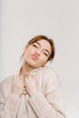 Funny brunette happy girl in beige sweater on white background