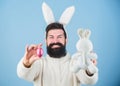 Funny bunny with beard and mustache hold pink egg. Bearded man wear bunny ears. Egg hunt. Look what i found. Hipster