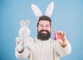 Funny bunny with beard and mustache hold pink egg. Bearded man wear bunny ears. Egg hunt. Look what i found. Hipster