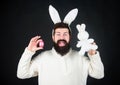 Funny bunny man with easter egg and toy. Easter activities concept. Egg hunt game. Guy bearded hipster cute gentle bunny