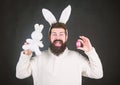 Funny bunny man with easter egg and toy. Easter activities concept. Egg hunt game. Guy bearded hipster cute gentle bunny