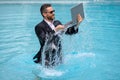 Funny business man in business suit with laptop jumping in splash water in the pool. Remote work. Crazy freelancer Royalty Free Stock Photo