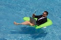 Funny business man in a business suit floating in the water in the pool. Remote summer work online. Crazy freelancer Royalty Free Stock Photo
