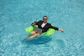 Funny business man in a business suit floating in the water in the pool. Remote work. Crazy freelancer. Business and Royalty Free Stock Photo