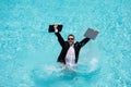 Funny business man in business suit with laptop standing in the water in the pool. Remote work. Crazy freelancer Royalty Free Stock Photo