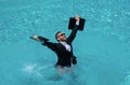 Funny business man in business suit with laptop standing in the water in the pool. Remote work. Crazy freelancer