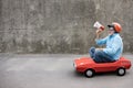 Funny businessman driving retro pedal car outdoor Royalty Free Stock Photo