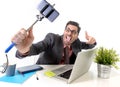 Funny businessman at office desk taking selfie photo with mobile phone camera and stick Royalty Free Stock Photo