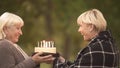 Funny cake joke, happy senior woman congratulating female friend on birthday
